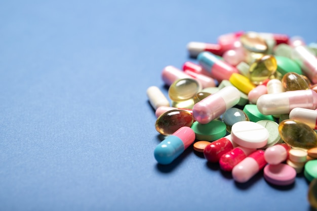 Pills and capsules on a blue background, place for text.