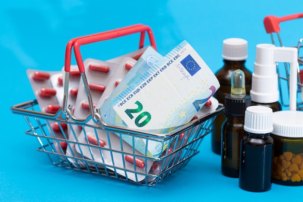 Pills and capsules in shopping cart on blue background