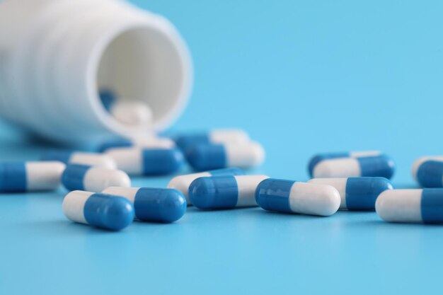 Pills capsules with bottle isolated on blue background