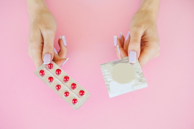 Pills and condom lie on a pink Background