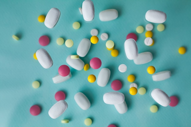 Pills of different colors and shapes on a blue background