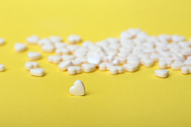 Pills in the form of hearts on a yellow background