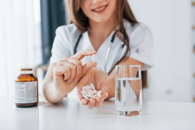 Foto pillole e bicchiere d'acqua l'operatore medico professionista in camice bianco è in ufficio