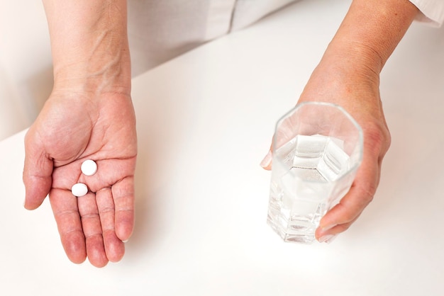 pills in a human hand and a glass of water. View from above
