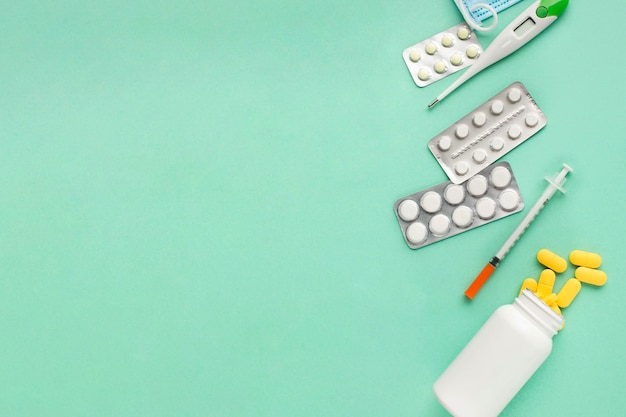 Pills and medical tools over green surface with space for text