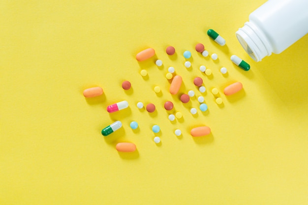 Таблетки и бутылки с лекарствами на желтом фонеВсе виды лекарств, которые нужно положить в лекарство