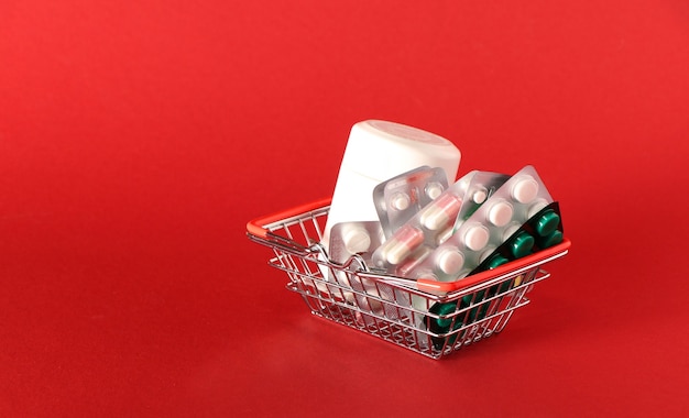 赤い背景の上の買い物かごのクローズアップの丸薬と薬