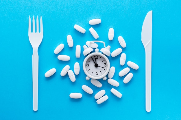 pills near knife and fork on a blue background