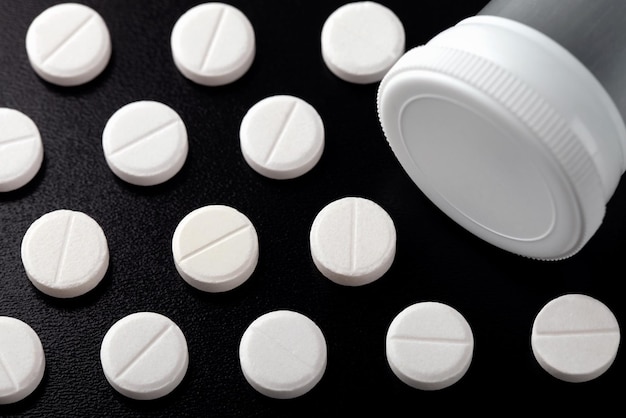 Photo pills organized and arranged around the safety cap of a pill bottle