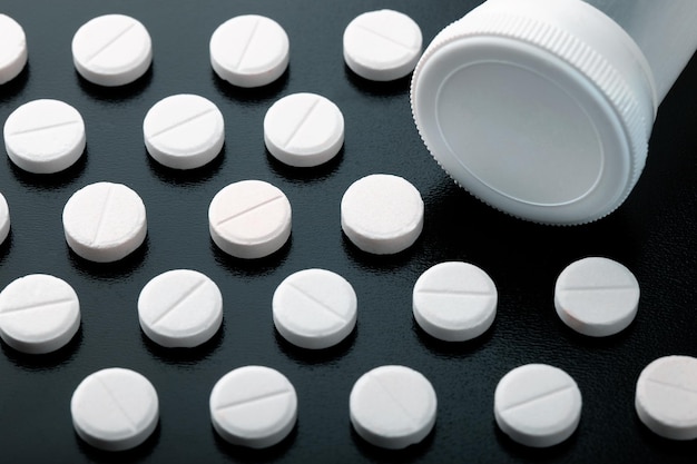 Photo pills organized and arranged around the safety cap of a pill bottle