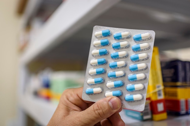 pills in the package hand holding pills in a pharmacy with a blurred background
