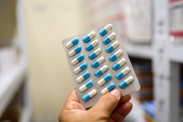 pills in the package hand holding pills in a pharmacy with a blurred background