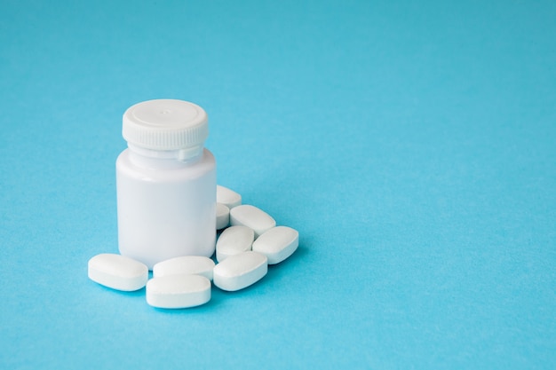 Pills and pill bottle on blue background