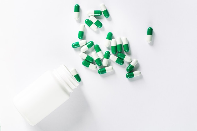 Pills and pill bottle on white background