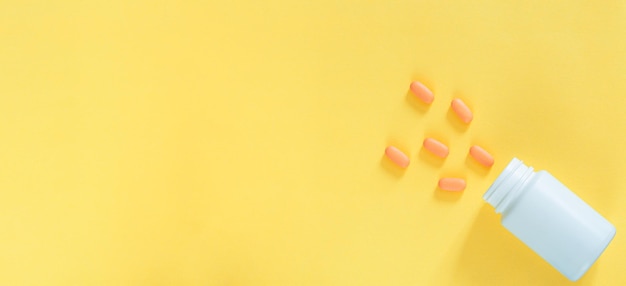 Pills and pill bottles on yellow background,Brown medical glass drug bottle and some pills around