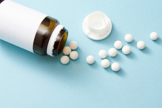 Pills poured from a jar on a blue surface