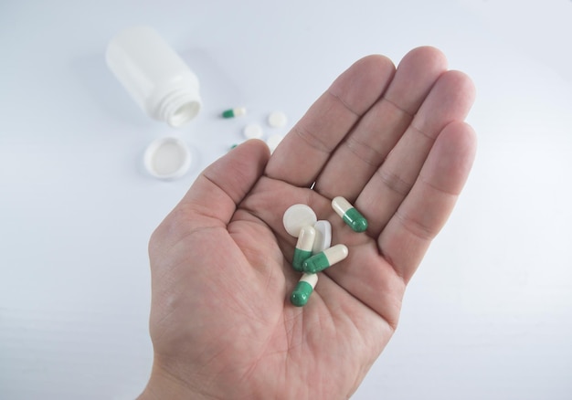 Pills poured into the palm from a jar that lies on a white table