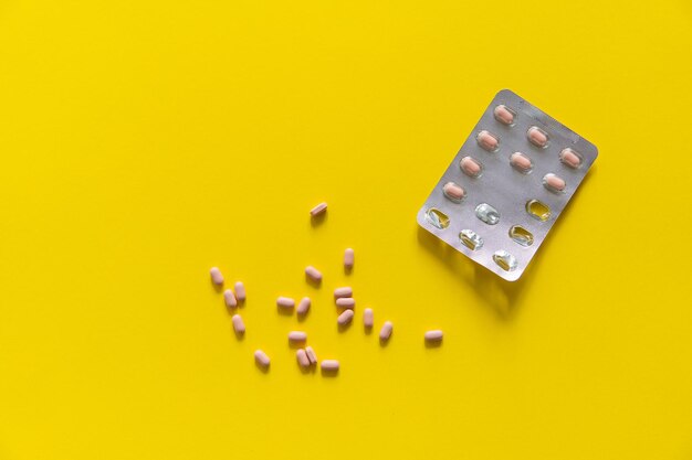 Pills removed from the pack Pink pills on yellow background Medicine medication Pharmacy theme