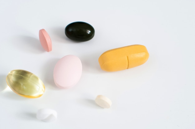 Pills in a row, various forms, white background. Multi-colored pills close-up 