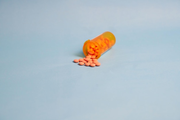 Pills and safety lid bottle on blue background