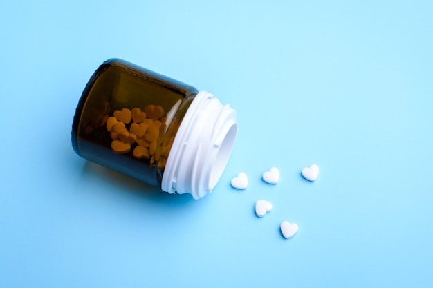 Pills in the shape of hearts on blue background