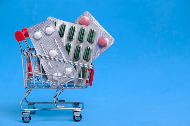 Pills in a shopping cart on blue background