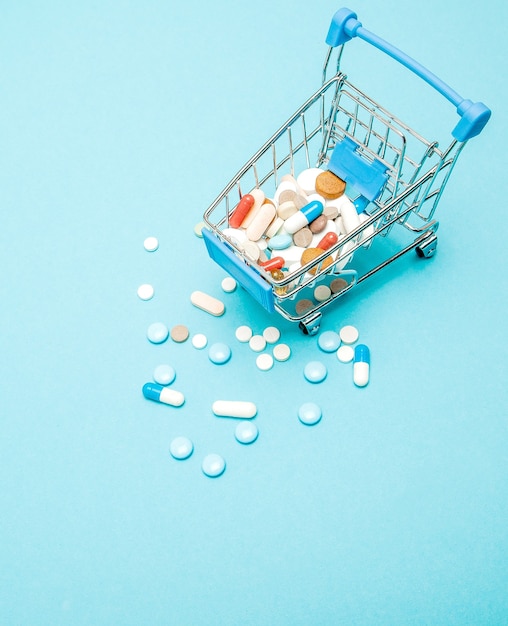 Pills and Shopping trolley on blue background