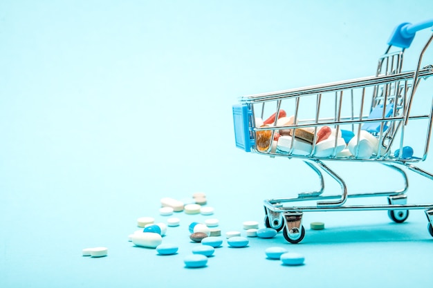 Pills and Shopping trolley on blue background