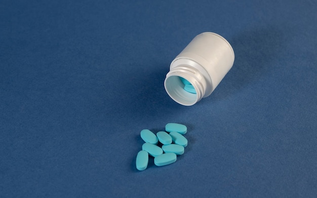 Pills spilled from a jar isolated on dark blue