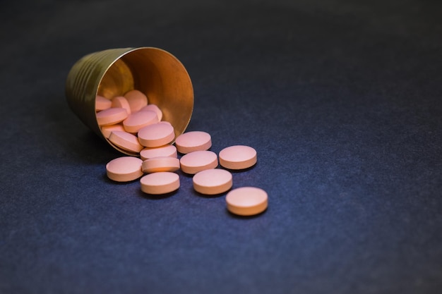 Pillole fuoriuscite da un piccolo bicchiere concetto di assistenza sanitaria e cure mediche contesto