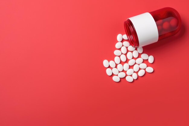 Pills spilling out of pill bottle on red background