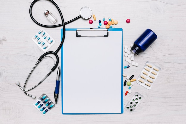 Pills and stethoscope around clipboard