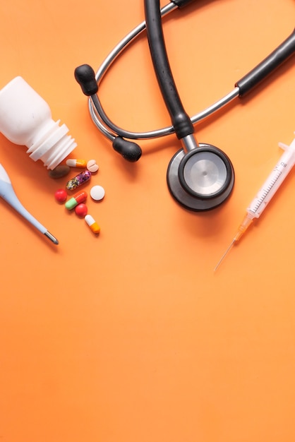 pills, stethoscope, thermometer and syringe on color