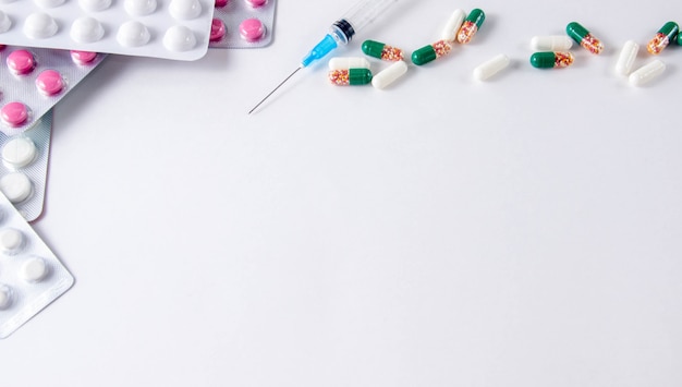 Pills and syringe on grey background