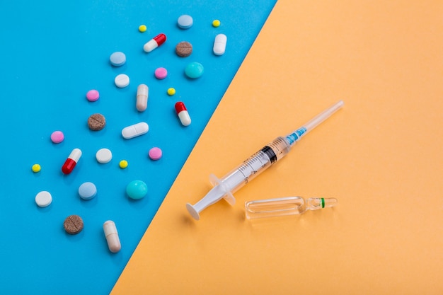 Pills and syringe with injection as a symbol of choice antibiotics against vaccine from Covid19