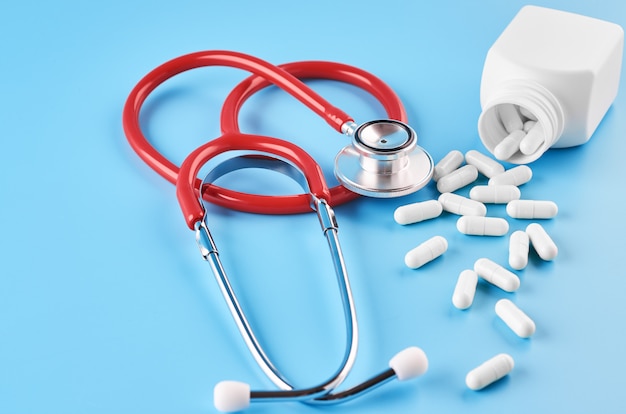 Pills tablets capsules closeup. On a blue background, a jar of medicine. On a blue background, a jar of medicine and a stethoscope.