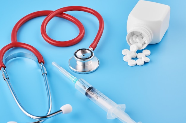 Таблетки таблетки капсулы крупным планом. На синем фоне баночка с лекарством. На синем фоне баночка с лекарством и стетоскоп.