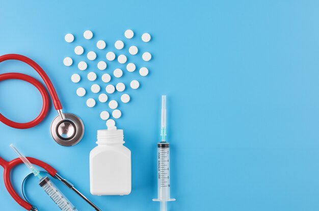 Pills tablets capsules closeup. On a blue background, a jar of medicine. On a blue background, a jar of medicine and a stethoscope.