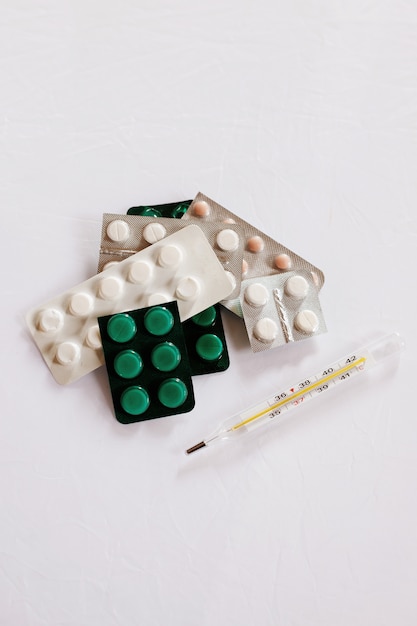 pills and thermometer on a white table