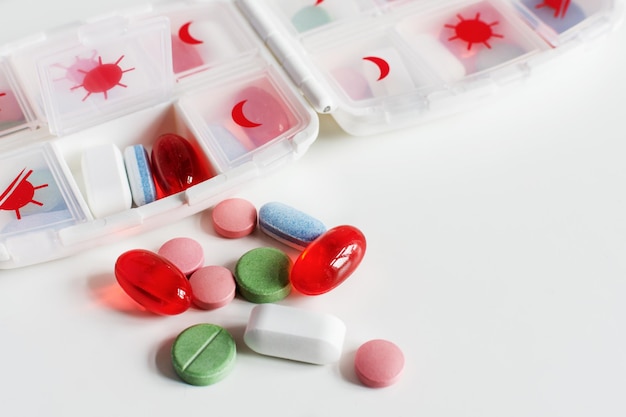 Pills and vitamins in a pill box organizer on white table