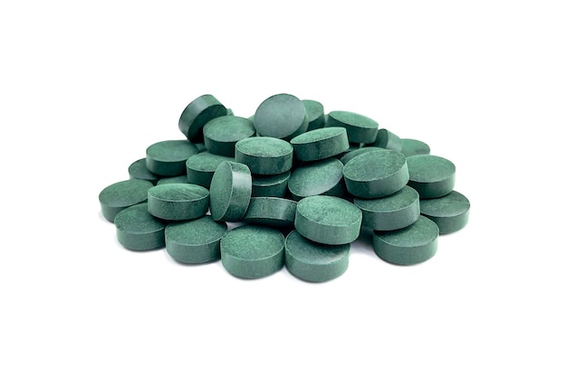 Pills on a white background from blue-green algae spirulina with a light shadow.