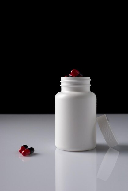 Pills in white bottle on black background