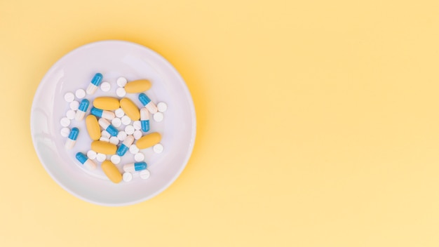 Pills on white plate over the yellow background