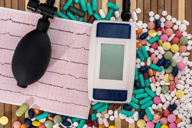 Pills with cardiogram and tonometer on wooden table