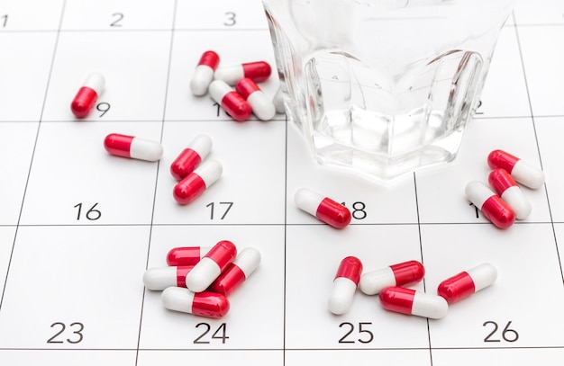 Pills with glass of water on the calendar