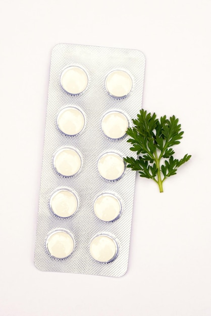 Pills with sprigs of plants on a white background