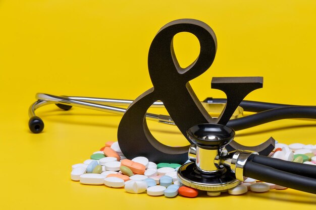 Pills with stethoscope and symbol on yellow background