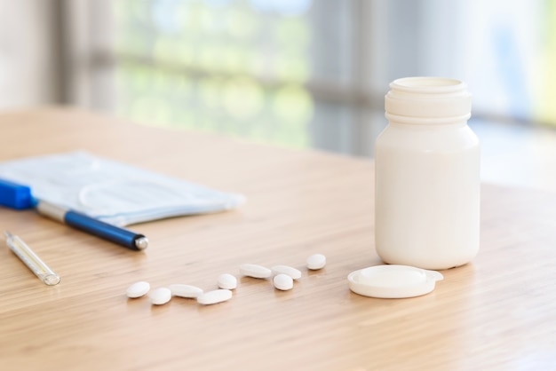 Pills with white plastic medicine bottle on the table