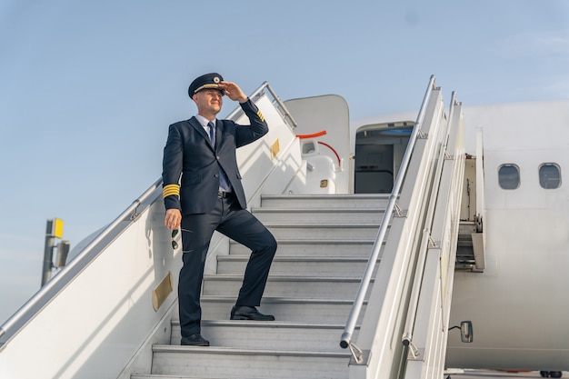 Pilot in a black suit standing on stairs of aircraft