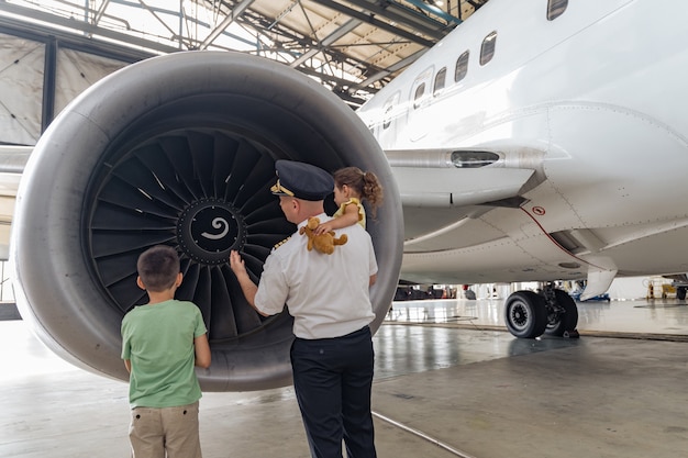 Pilot and children are standing near the turbine and looking at it